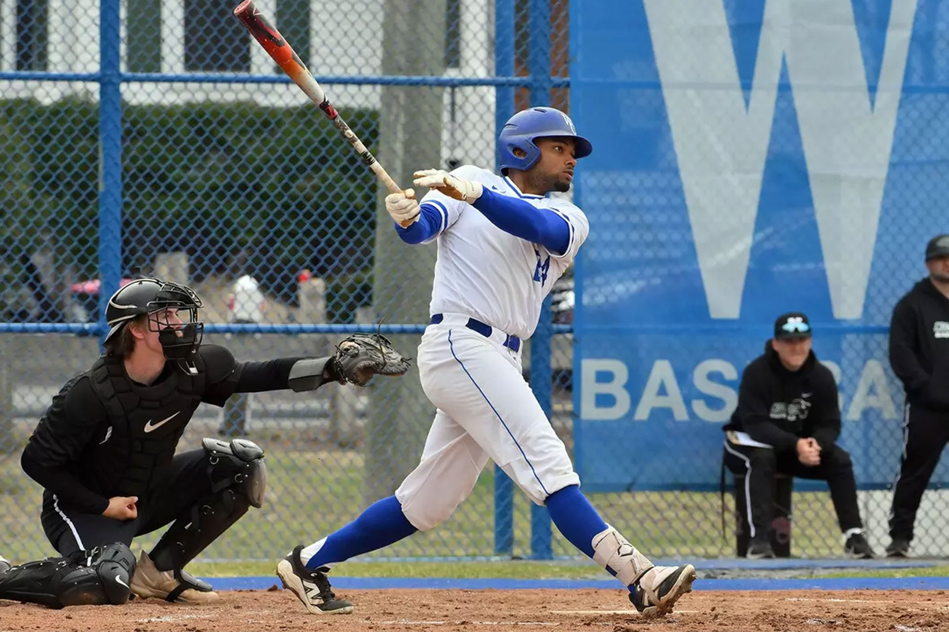 Member of Wheaton's baseball team swinging a bat during a game.